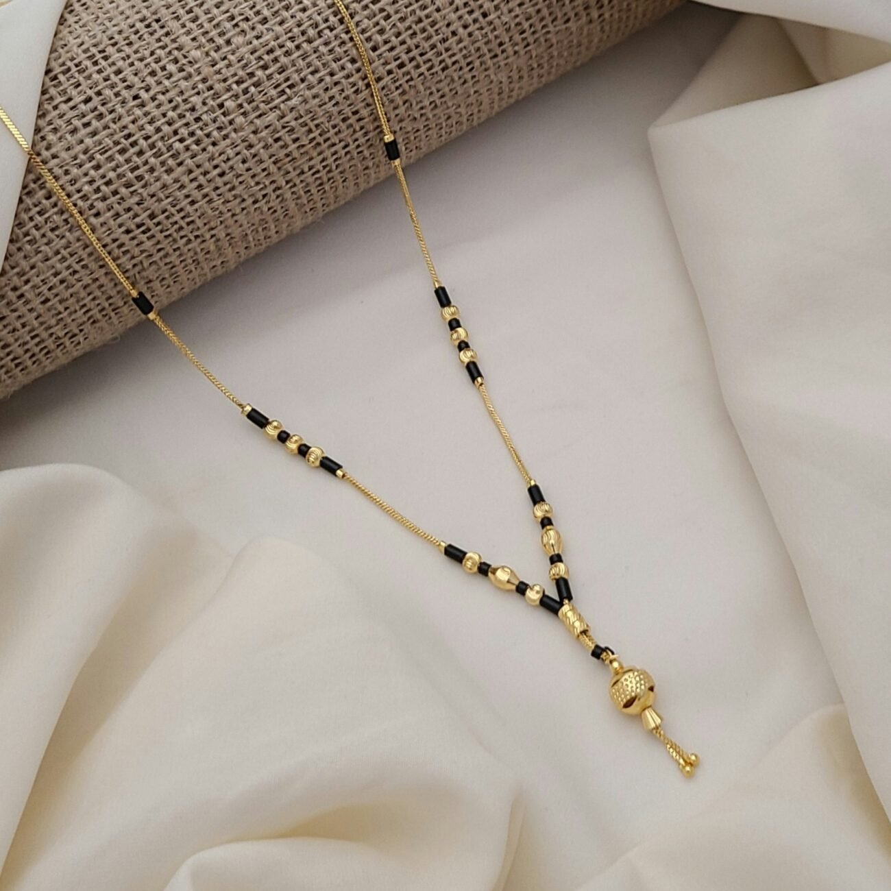 Collar minimalista en formato borla dorado con cuentas en color negro